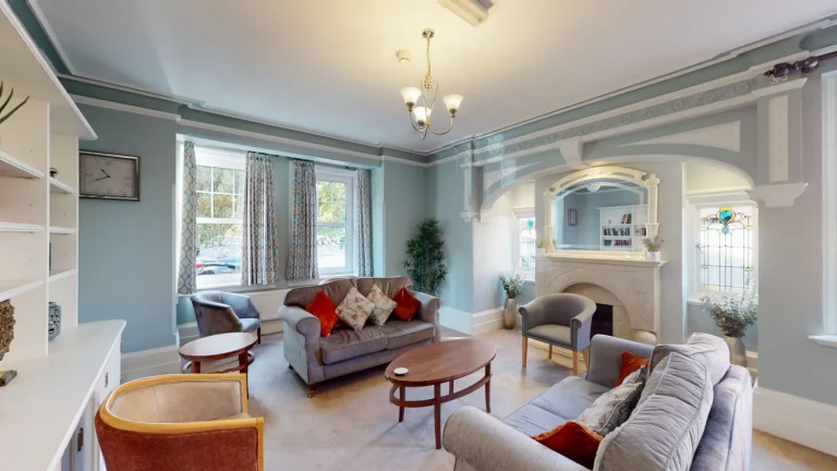 Image of Asana Lodge living space with comfy two seater sofas, chairs, and a fireplace