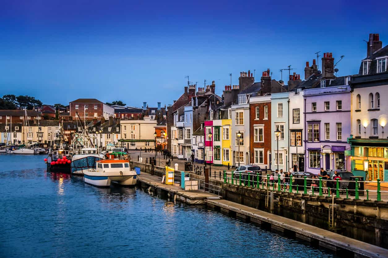 Row of colourful houses with small boats docked in front of them